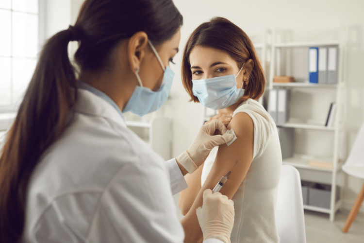 Zdjęcie przedstawia pielęgniarkę szczepiącą pacjentkę przeciw COVID-19